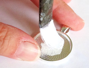 applying glue to the base of a jewelry blank