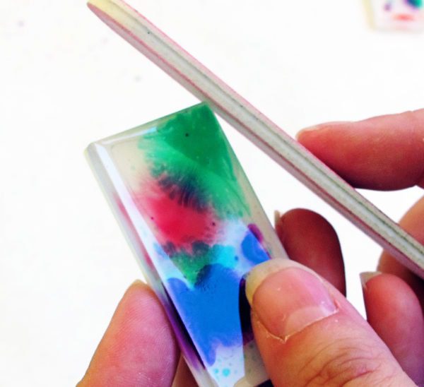 sanding edges of a resin charm with a nail file