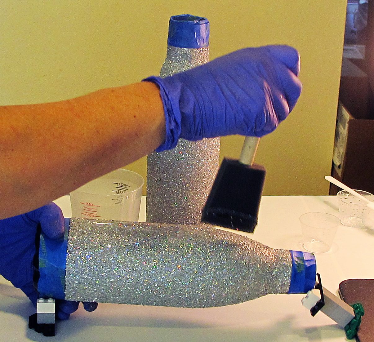 applying resin to a stainless steel tumbler with a foam brush