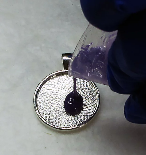 pouring purple resin into a pendant blank