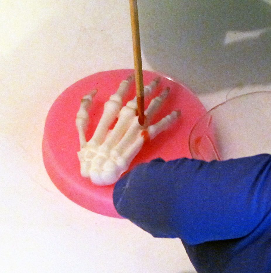 adding red resin drips to a skeleton hand