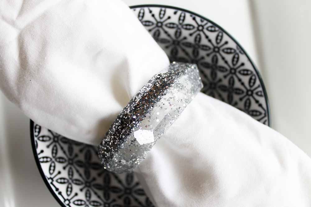 silver glitter resin napkin rings silver on black and white dish close up