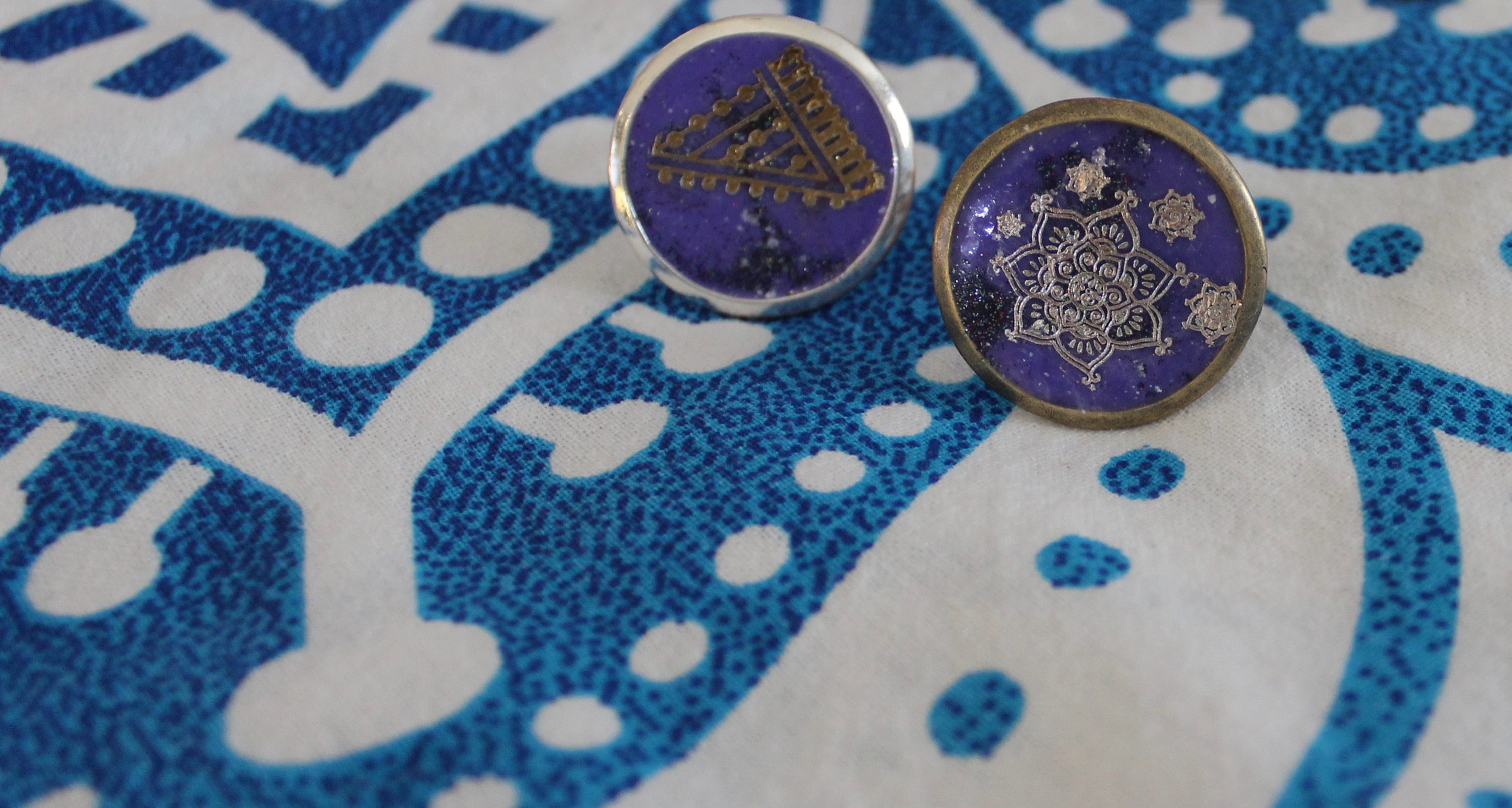 Front view of two rings with gold mandala designs on deep purple resin background