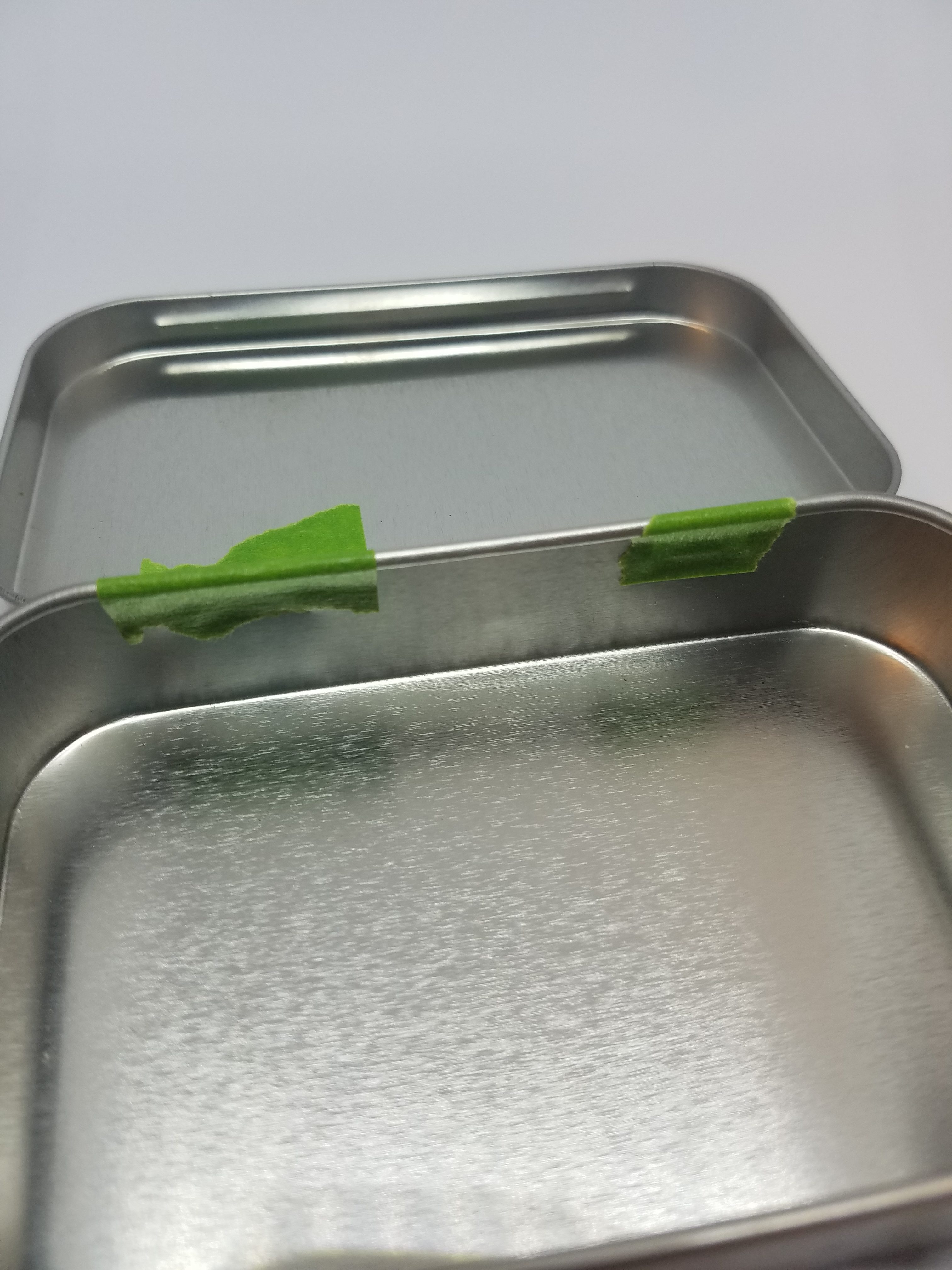green tape on the hinges of the empty mint tin
