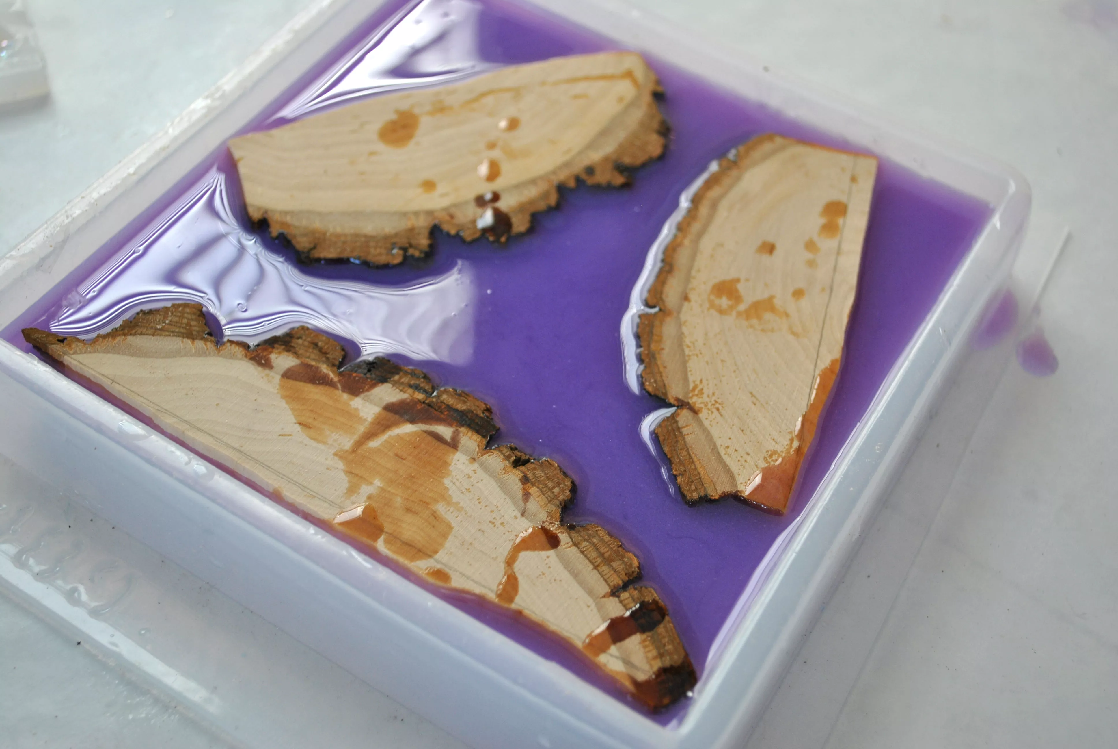 three cuts of wood and lavender resin mixture in square resin mold