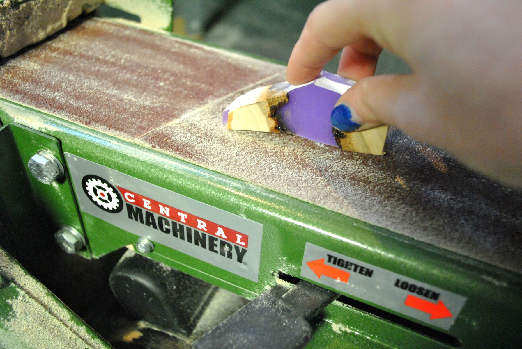 holding wood and lavender resin charm on belt sander surface