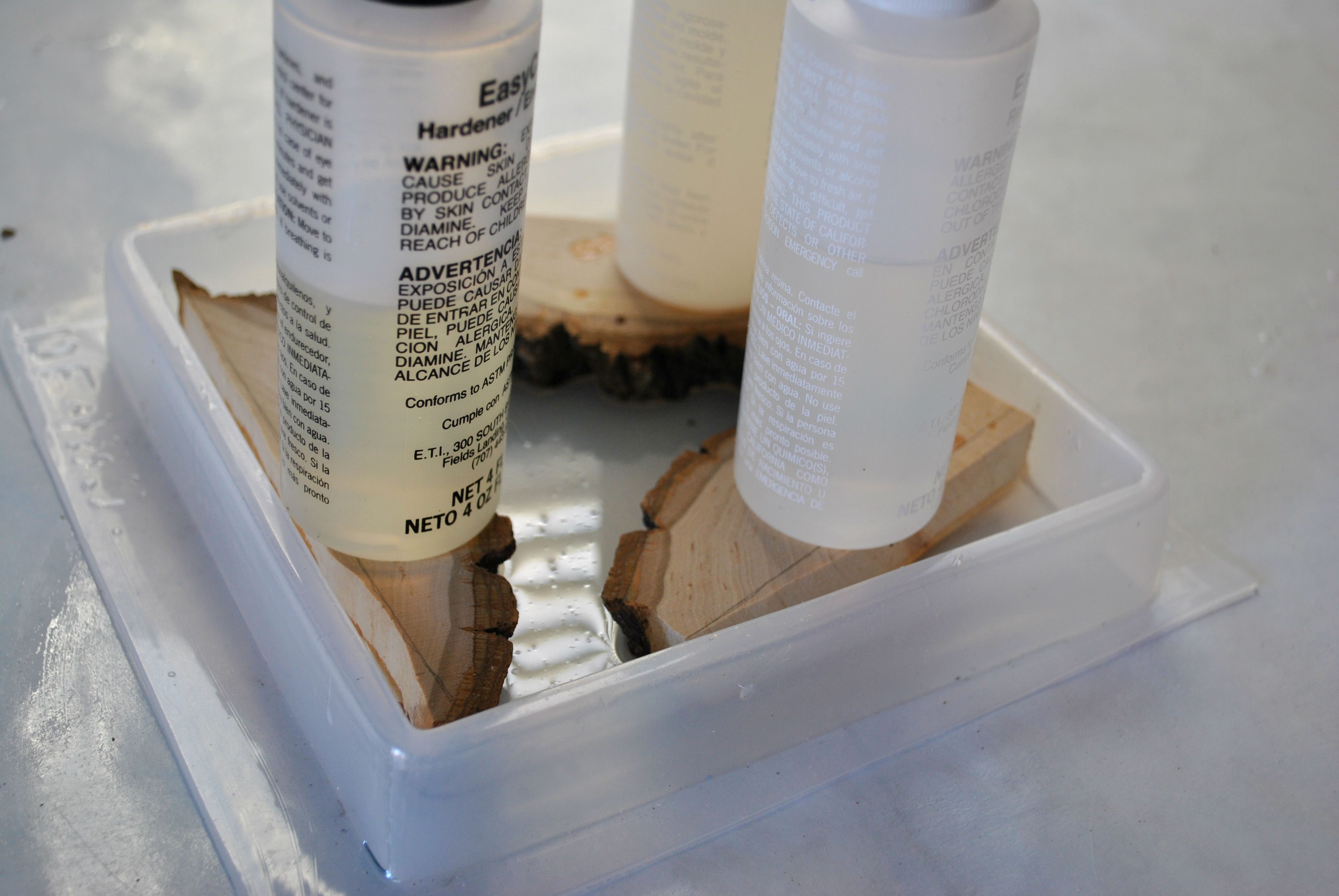 three pieces of cut wood in a resin mold with small plastic bottles used as weights 