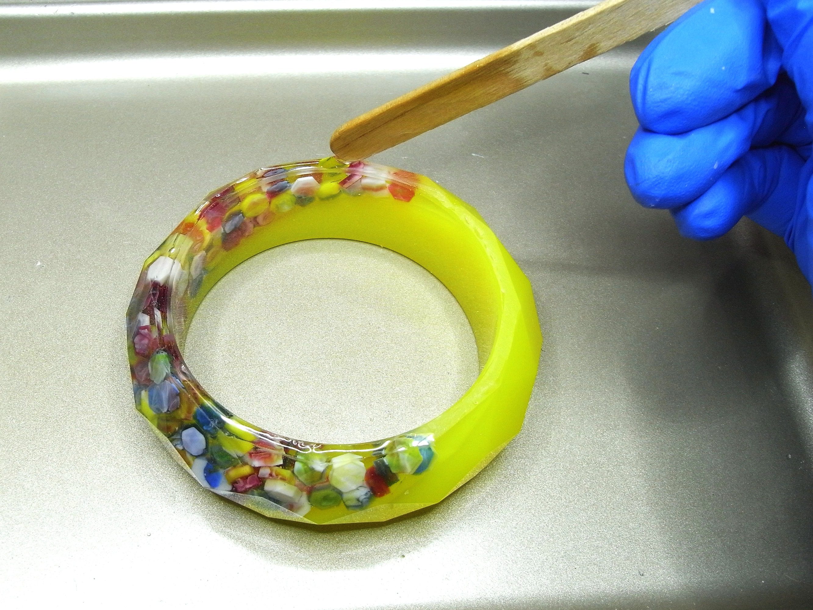 applying resin to bangle with wooden stir stick