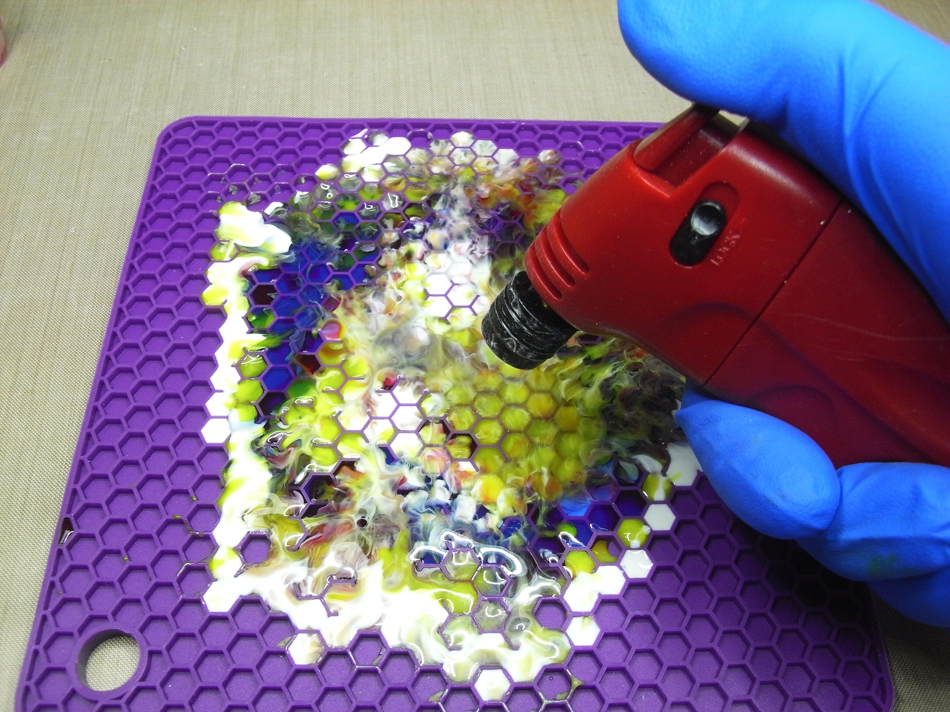 passing a flame across the resin to pop bubbles