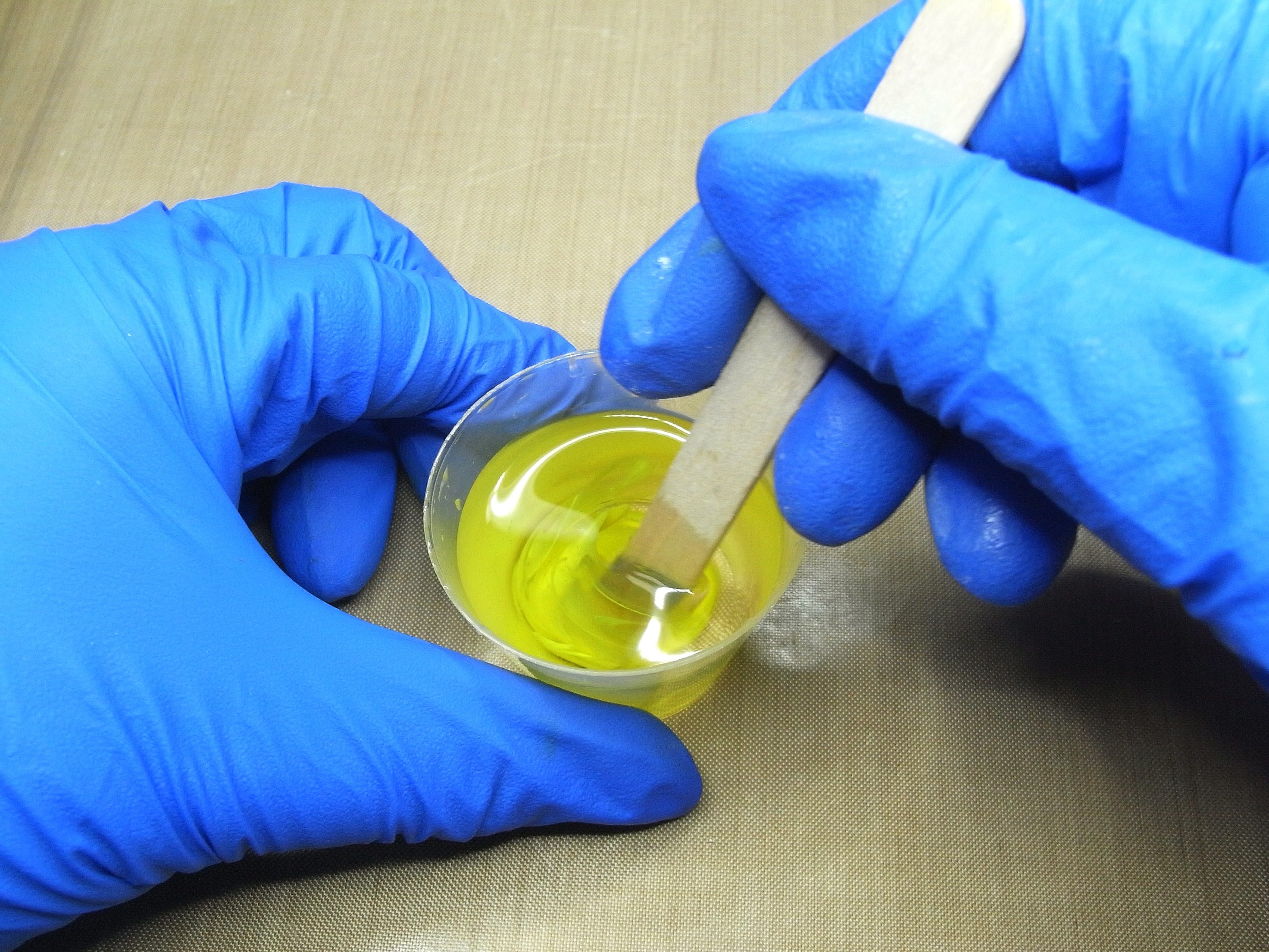 mixing resin with wooden stirrer in plastic cup