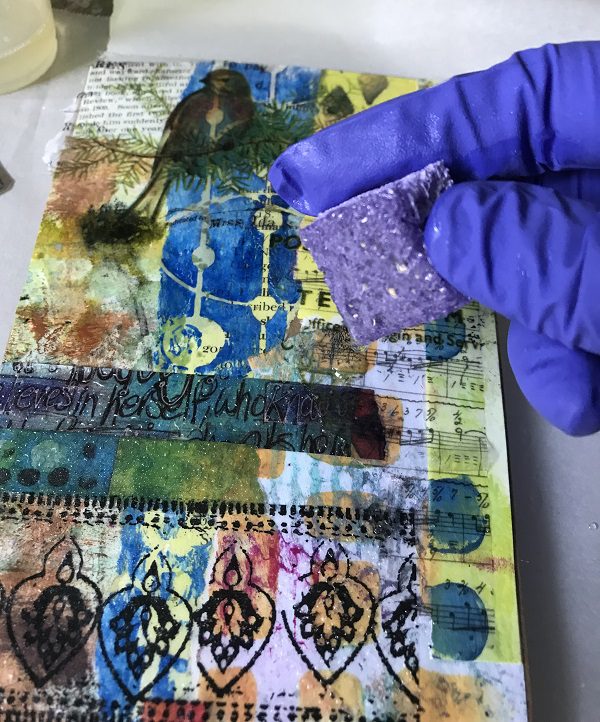 spreading resin over art journal cover with sponge