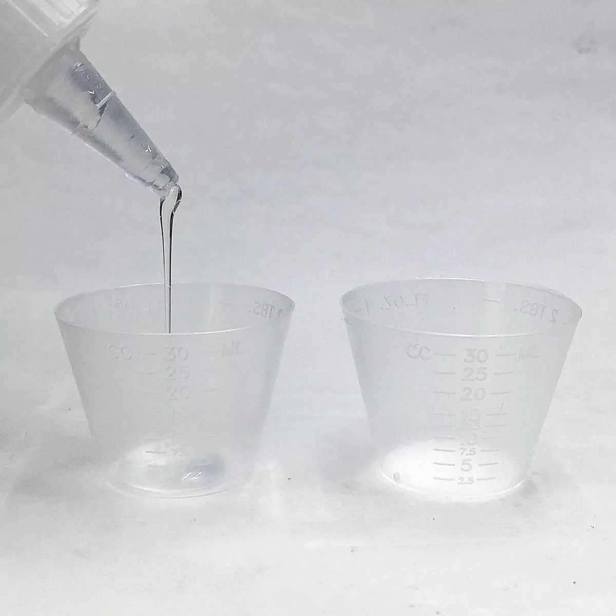 measuring epoxy resin and hardener into graduated resin mixing cups