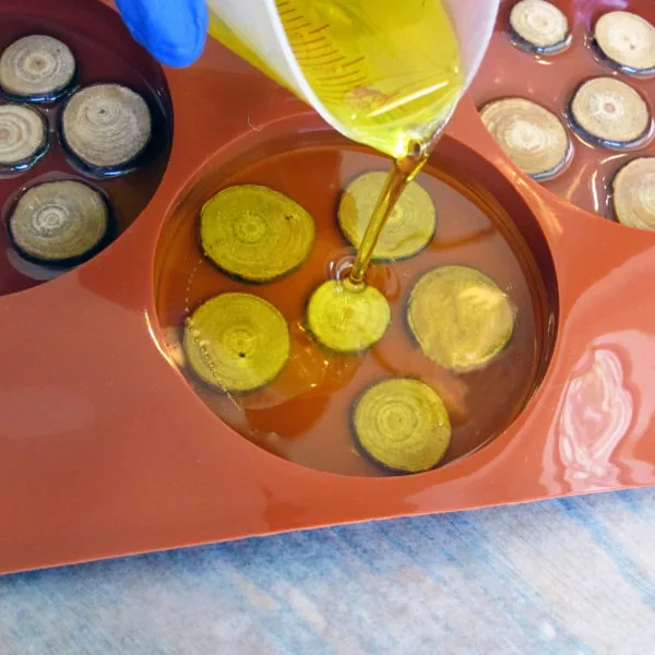pouring yellow resin into a silicone coaster mold