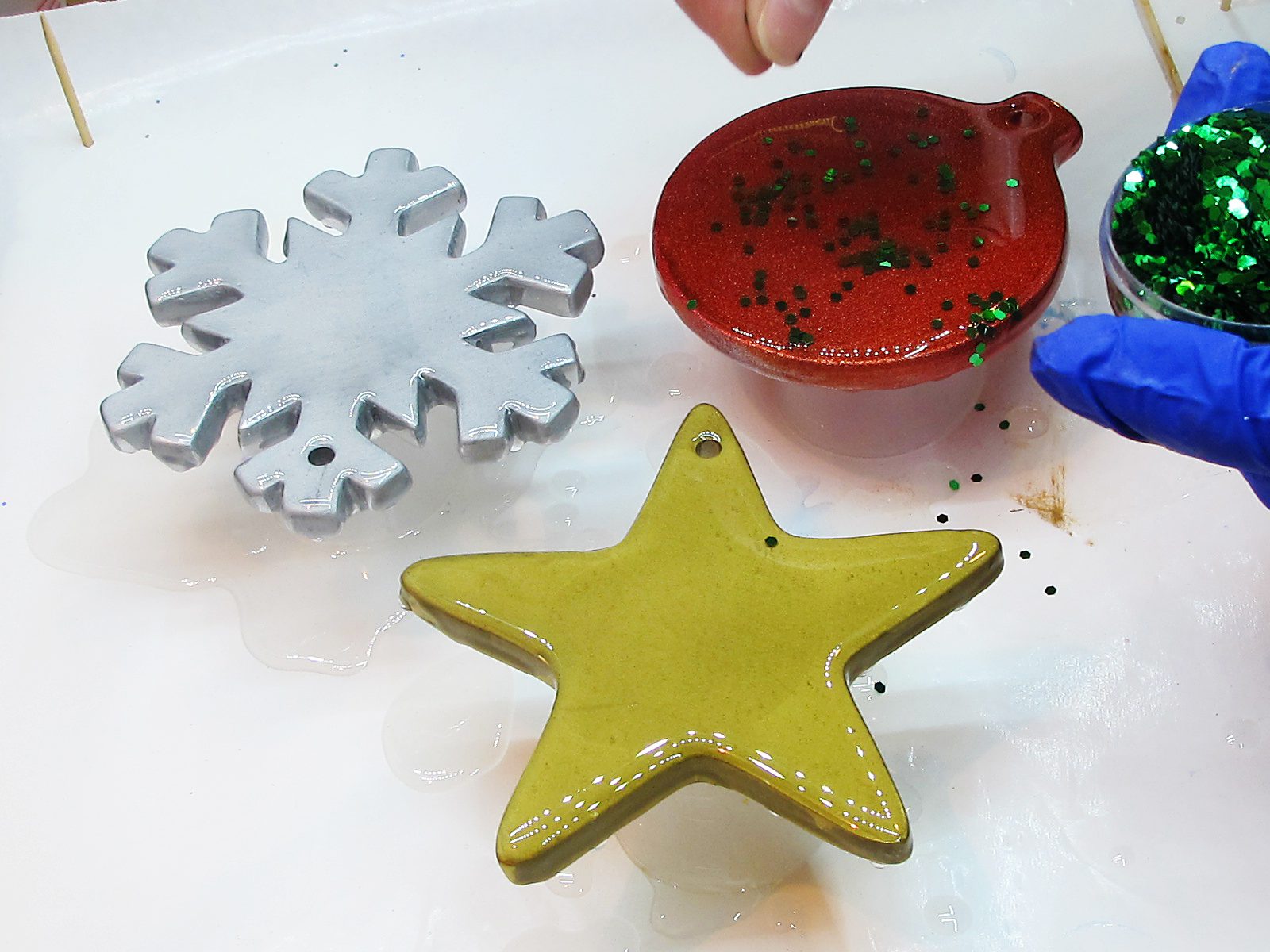Sprinkling green glitter on a red ornament with resin.