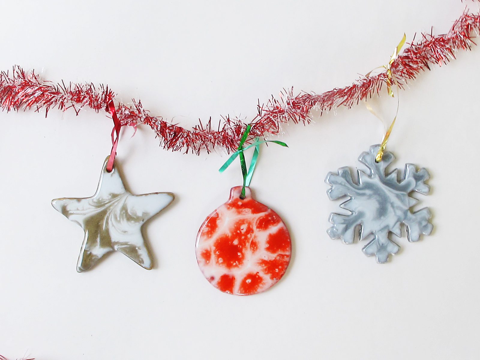 Three resin Christmas ornaments hanging from a red garland.