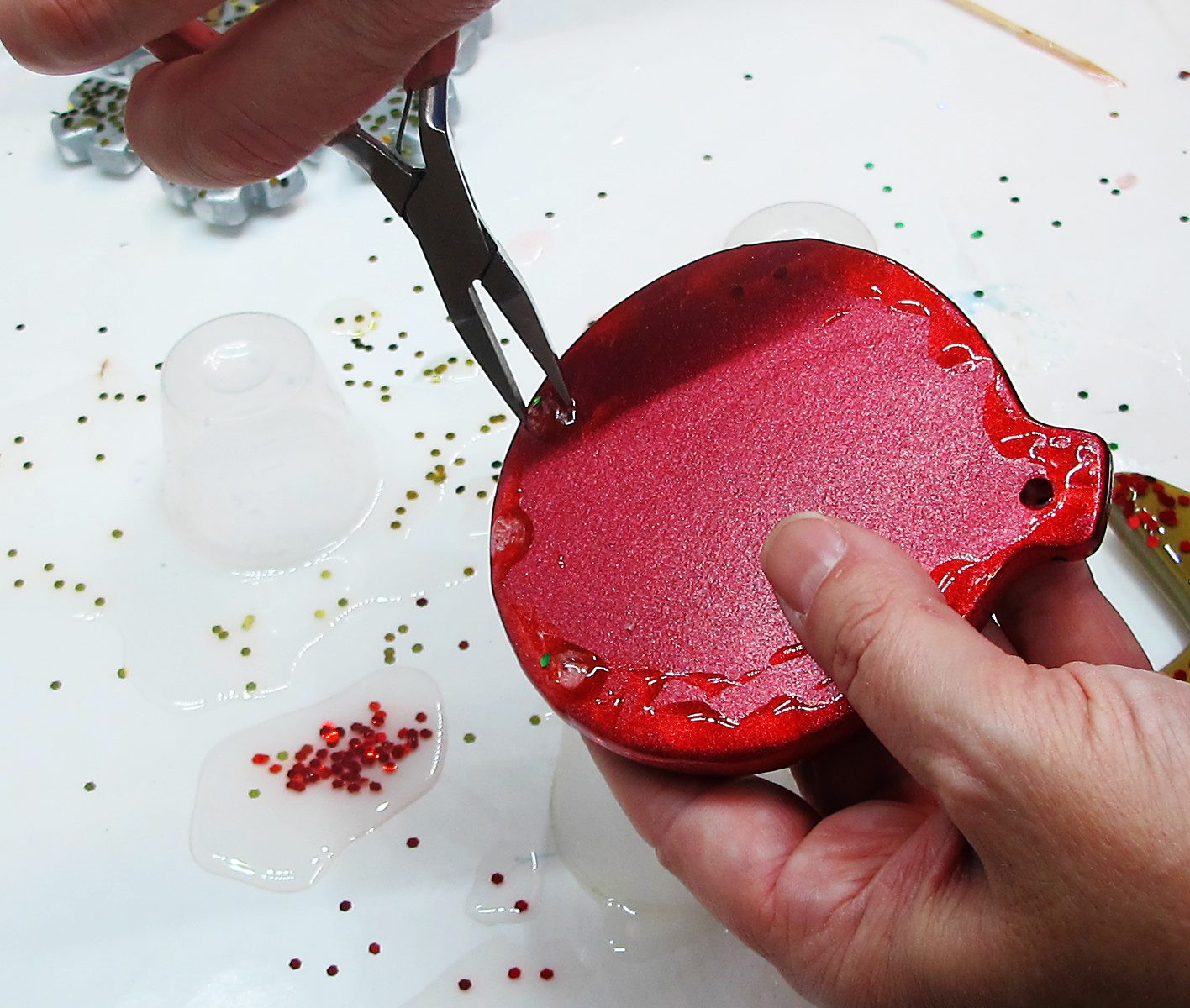 Trimming resin drips on an ornament with pliers.
