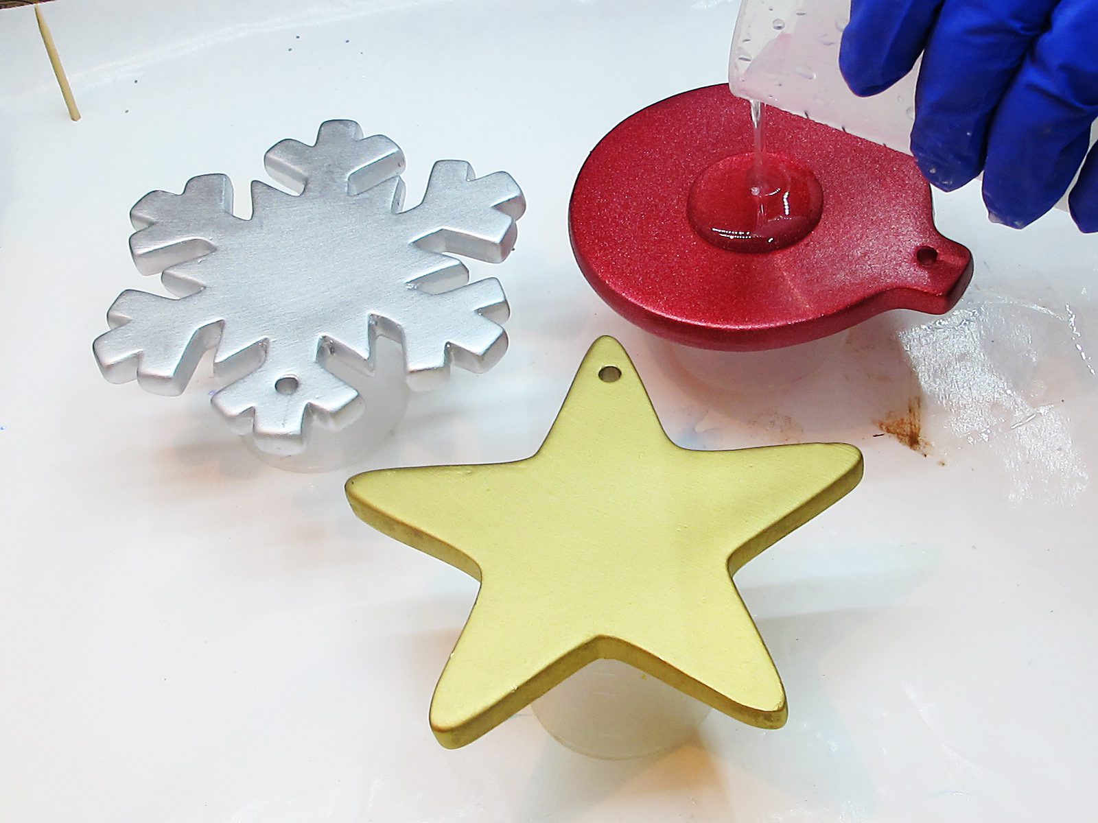 Pouring resin onto Christmas ornaments.