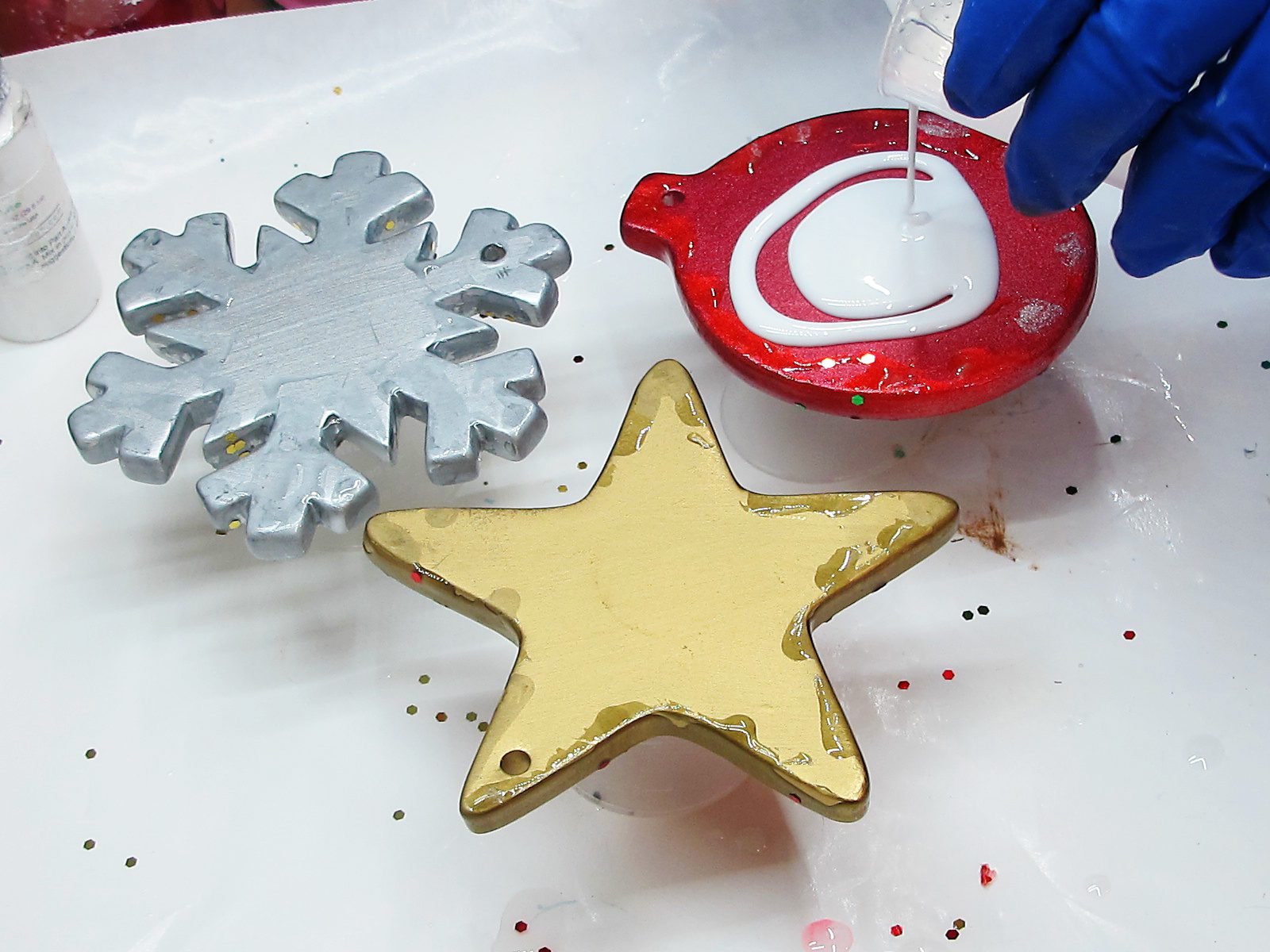 Pouring white resin on Christmas ornaments.