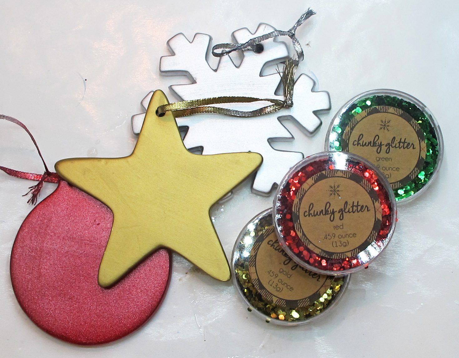 Three painted resin ornaments with three colors of glitter.