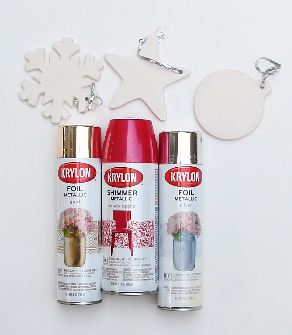 Three spray paint cans with three plain ornaments.