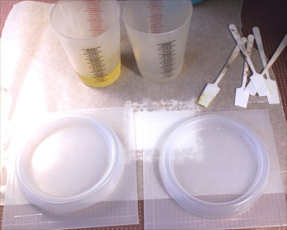 Two plastic molds with cups of resin and stir sticks.