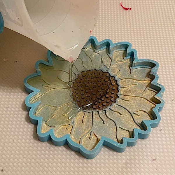 adding clear resin to a coaster mold
