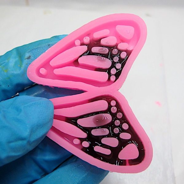 rolling epoxy along the bottom of a butterfly wing silicone mold