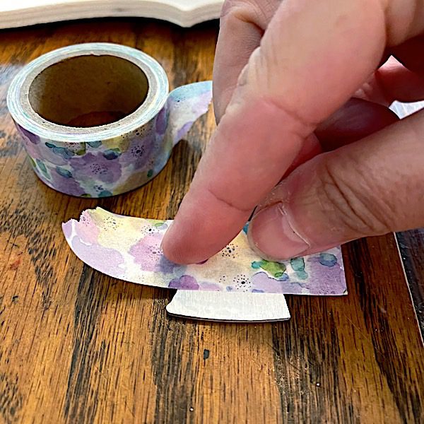 pressing washi tape onto a wood cutout